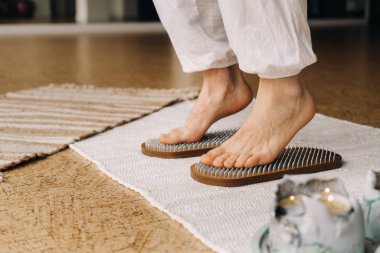 Adamın ayakları çivili tahtaların yanında. Yoga dersleri.