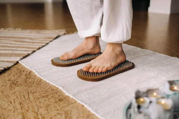 The man\'s feet are next to boards with nails. Yoga classes.