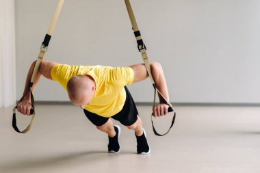 Odaklanmış bir erkek sporcu spor salonunda fonksiyonel döngüler üzerinde bir egzersiz yapıyor..