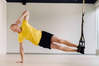 Odaklanmış bir erkek sporcu spor salonunda fonksiyonel döngüler üzerinde bir egzersiz yapıyor..