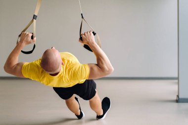 Odaklanmış bir erkek sporcu spor salonunda fonksiyonel döngüler üzerinde bir egzersiz yapıyor..