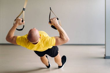 Odaklanmış bir erkek sporcu spor salonunda fonksiyonel döngüler üzerinde bir egzersiz yapıyor..