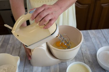 Adım adım ekşi kremalı turta hamuru yapma süreci. Karıştırıcı hamur kasesindeki yumurtaları çırpıyor. Pişirme kavramı.