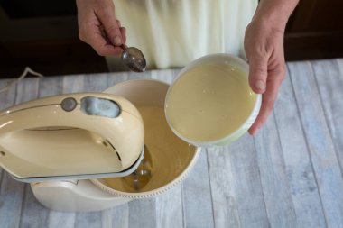 Adım adım ekşi kremalı turta hamuru yapma süreci. Kadın eli, hamur yapmak için karıştırıcı kasesine süt ekler. Pişirme kavramı.