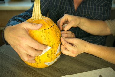 Jack O 'Lantern' i evde yapmak. Bir Jack O 'Lantern tema şablonu oluşturma süreci. Bir erkek ve bir kadın oymak için balkabağı hazırlıyorlar..