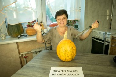 Jack O 'Lantern' i evde yapmak. Jack O 'Lantern şablon oluşturma işlemi. Bir kadın balkabağını oymaya hazırlar. Kadın işinden memnun, gülüyor ve şakalaşıyor..