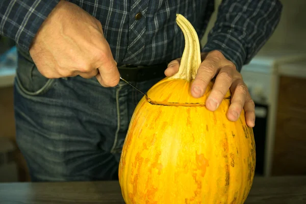 ハロウィンだ ジャック オランタンを家で作る方法は ナイフで男性の手 キッチンテーブルの上にカボチャの残り物 選択的焦点とボケ — ストック写真