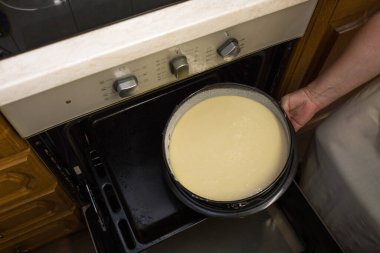 Ekşi kremalı çikolatalı pasta yapmak için adım adım bir işlem. Dişi eller pişmiş hamuru hazır bir fırına koyar. Pişirme kavramı.