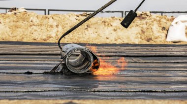 Bir kaynak makinesi kullanarak çatı malzemesi yerleştirme işlemi. Bituminous keçesi kurulum sırasında erir. Yumuşak çatı.