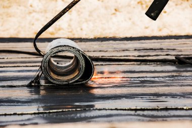 Bir kaynak makinesi kullanarak çatı malzemesi yerleştirme işlemi. Bituminous keçesi kurulum sırasında erir. Yumuşak çatı.
