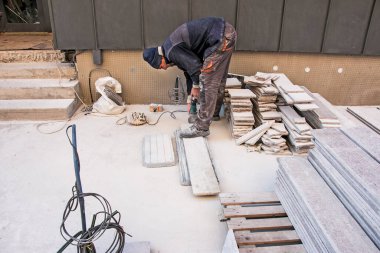 Dnepropetrovsk, Ukrayna - 10.22.2021: Bir adam granit levhayı öğütücüyle parlatır.