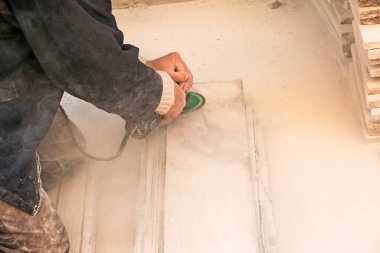 Bir adam granit levhayı öğütücüyle parlatıyor. Açı öğütücüsüyle taş üzerinde çalış. Bir işçi beyaz bir taşı parlatır..