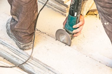 Bir adam granit levhayı öğütücüyle parlatıyor. Açı öğütücüsüyle taş üzerinde çalış. Bir işçi beyaz bir taşı parlatır..