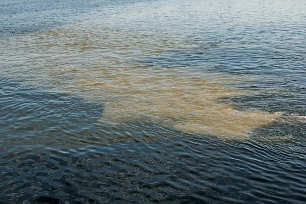 下水パイプラインからの汚れたオレンジの水は川の水と混合する 2つの異なる水流の間の明確な境界線 環境汚染のテーマ — ストック写真
