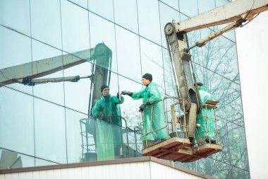 Dnepropetrovsk, Ukrayna - 30,10. 2021: Pencere temizleyicisi yükseklikte çalışıyor. Gözlüklerdeki yansımalar. Binanın cam cephesini temizliyorum..
