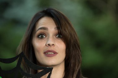 Koyu saçlı, yeşil gözlü güzel bir kadının portresi. Yüzü. Gülümse. Fotoğraf koyu yeşil arka planda bulanık.