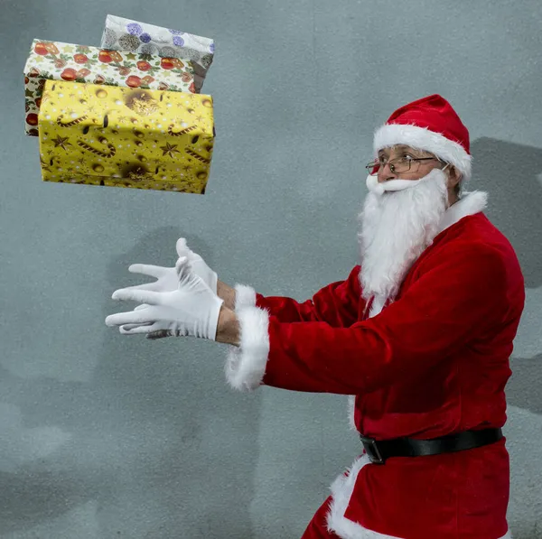 戴着红帽子的圣诞老人用手扔礼物 — 图库照片