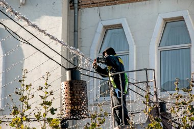 Dnepropetrovsk, Ukrayna - 11.14.2021: İşçiler yeni yıl tatilleri için bir şehir caddesini dekore ediyorlar. İşçiler tatil lambalarını yapay ağaçlara takarlar.