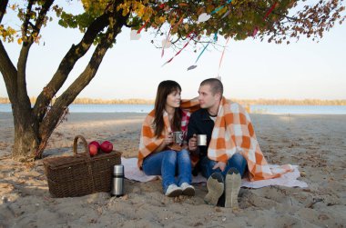 Bir çift aşık, nehrin kıyısında bir battaniyeyle kaplı bir ağacın altında oturuyorlar. Adam ve kız canlı bir sohbet eder ve demir bardaklardan çay içerler..