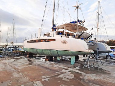 Bodrum, Türkiye - 10.12.2021: Tersanede modern yelken yatı. Tekne marinasının kıyısındaki limana yanaşmış bir spor yatı. Kairos Marina.
