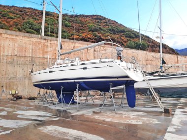 Bodrum, Türkiye - 10.12.2021: Tersanede modern yelken yatı. Tekne marinasının kıyısındaki limana yanaşmış bir spor yatı. Kairos Marina.