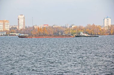 Eklemli bir römorkör ve toplu mavna nehir boyunca kum ve inşaat malzemeleri taşıyor. Geniş Dinyeper Nehri boyunca büyük bir mavna yelken açar. Ulaşım endüstrisi. Peyzaj.