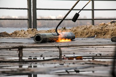 Bir kaynak makinesi kullanarak çatı malzemesi yerleştirme işlemi. Bituminous keçesi kurulum sırasında erir. Yumuşak çatı.