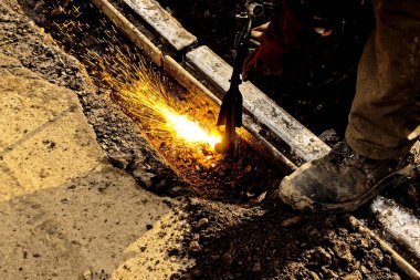 Demiryolu kesme işlemi üzerinde çalışan bir sanayi işçisinin eli. Bir erkek işçi plazma kesici kullanarak çeliği keser..