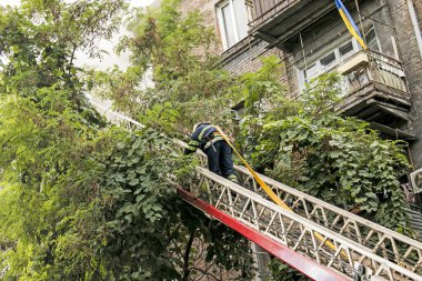 Dnepropetrovsk, Ukrayna -09.20.2021: Beş katlı bir binanın en üst katında yangın. İtfaiyeci merdivenlerden çıkıp yangın hortumunu çeker..