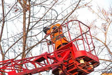 Dnepropetrovsk, Ukrayna - 11.24.2021: Kamyon vinçindeki belediye çalışanları şehrin sokaklarını Noel ışıklarıyla süslediler. Güneşli havada yüksek irtifa çalışması.