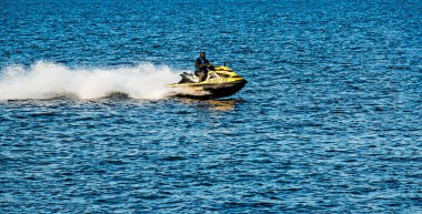 Dnepropetrovsk, Ukrayna - 10.31.2021: Dnepropetrovsk 'taki geniş Dnieper Nehri boyunca yarışan bir adamla bir jet ski. Yetişkin bir adam süzülerek mavi bir su yüzeyinin arka planına sıçrıyor.