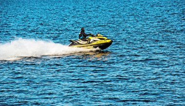 Dnepropetrovsk, Ukrayna - 10.31.2021: Dnepropetrovsk 'taki geniş Dnieper Nehri boyunca yarışan bir adamla bir jet ski. Yetişkin bir adam süzülerek mavi bir su yüzeyinin arka planına sıçrıyor.