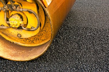 Küçük buharlı silindirler asfaltı dümdüz etmiş. Asfalt kaldırımda ağır titreşimli silindir çalışıyor. Tekerlek parçası, şehir yolu yapım aşamasında, asfaltlama devam ediyor.