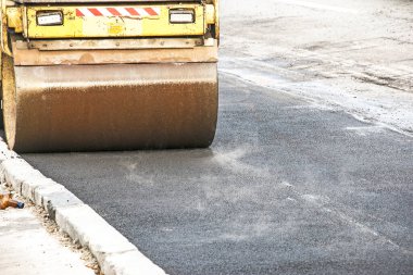 Küçük buharlı silindirler asfaltı dümdüz etmiş. Asfalt kaldırımda ağır titreşimli silindir çalışıyor. Tekerlek parçası, şehir yolu yapım aşamasında, asfaltlama devam ediyor.