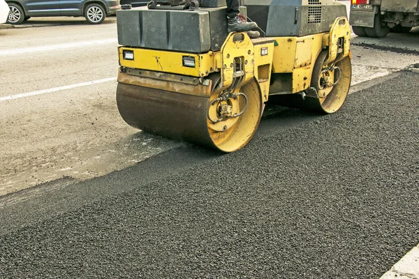 Küçük buharlı silindirler asfaltı dümdüz etmiş. Asfalt kaldırımda ağır titreşimli silindir çalışıyor. Tekerlek parçası, şehir yolu yapım aşamasında, asfaltlama devam ediyor.