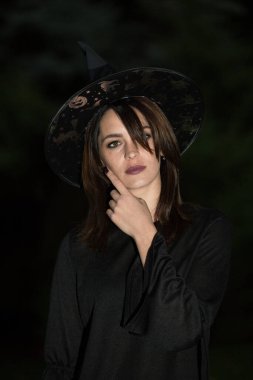 Geniş kenarlı şapkalı genç bir kadının portresi. Kız siyah bir elbise giyiyor. Duygu kavramı.