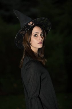 Geniş kenarlı şapkalı genç bir kadının portresi. Kız siyah bir elbise giyiyor. Duygu kavramı.