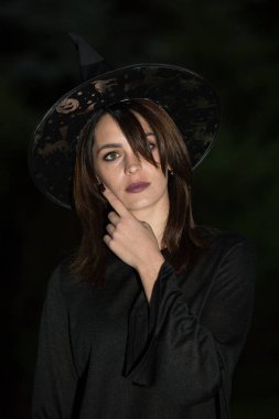 Geniş kenarlı şapkalı genç bir kadının portresi. Kız siyah bir elbise giyiyor. Duygu kavramı.