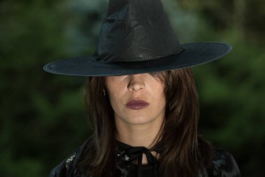 Geniş kenarlı şapkalı genç bir kadının portresi. Kız siyah bir elbise giyiyor. Duygu kavramı.