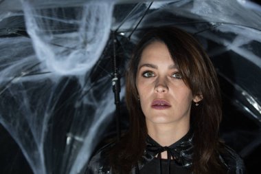 Cadılar Bayramı pikniğinde örümcek ve örümcek ağlarıyla şemsiyenin altında güzel bir genç kadın. Sıcak bir sonbahar ekim akşamı. Büyülü bir ruh hali. Duygu kavramı.