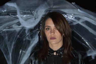 Cadılar Bayramı pikniğinde örümcek ve örümcek ağlarıyla şemsiyenin altında güzel bir genç kadın. Sıcak bir sonbahar ekim akşamı. Büyülü bir ruh hali. Duygu kavramı.