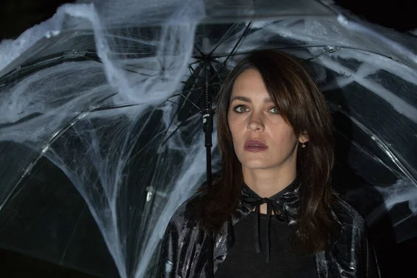 Cadılar Bayramı pikniğinde örümcek ve örümcek ağlarıyla şemsiyenin altında güzel bir genç kadın. Sıcak bir sonbahar ekim akşamı. Büyülü bir ruh hali. Duygu kavramı.