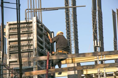 Yüksek bir binanın inşaatı. İşçiler beton dökmek için hazırlık yapıyorlar.