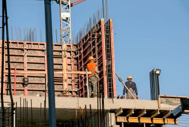 Yüksek bir binanın inşaatı. İşçiler beton dökmek için hazırlık yapıyorlar.