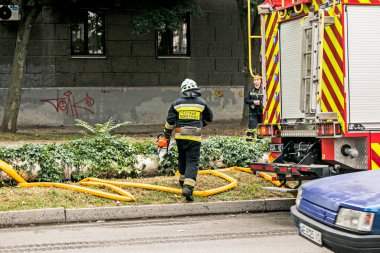 Dnepropetrovsk, Ukrayna -09.20.2021: Beş katlı bir binanın en üst katında yangın. İtfaiyeci, yangın yerine elektrikli testereyle koşar..