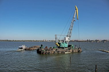 Yeni kurulan adayı Dinyeper 'daki endüstriyel atıklardan bir eşeleyiciyle temizlemek. Römorkörlü bir mavna çöpü dışarı çıkarır. Ekoloji kavramı.