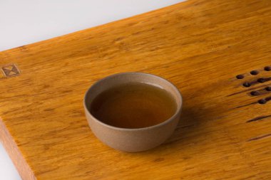 Traditional ceramic cup on a wooden table for tea eremonies. The cup is filled with freshly brewed green tea.