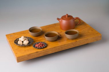 A teapot and three cups of freshly brewed pu-erh tea, pressed sugar. A set on a wooden table for tea ceremonies.