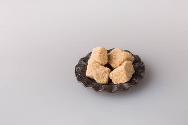 Esmer, rafine edilmemiş kamış şekeri, arka planda bir fincan altlığında..