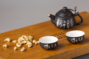 İki geleneksel Asya çay fincanı ve bir çaydanlık. Çay seremonileri için ahşap bir masada servis ve fındık. Minimalizm kavramı.